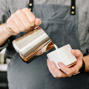 Barista tejet önt polírozott rozsdamentes acél kannából, az Espresso kiegészítők és tejkanna része, mindent a kávéról.