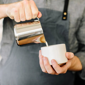 Barista tejet önt polírozott rozsdamentes acél kannából, az Espresso kiegészítők és tejkanna része, mindent a kávéról.
